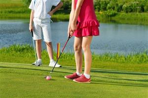 Young lady wearing a pink outfit practicing putting.
